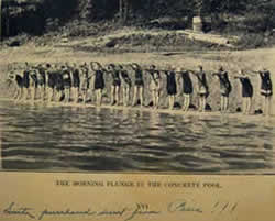 Girls lined up along edge of concrete swimming pool in the creek.